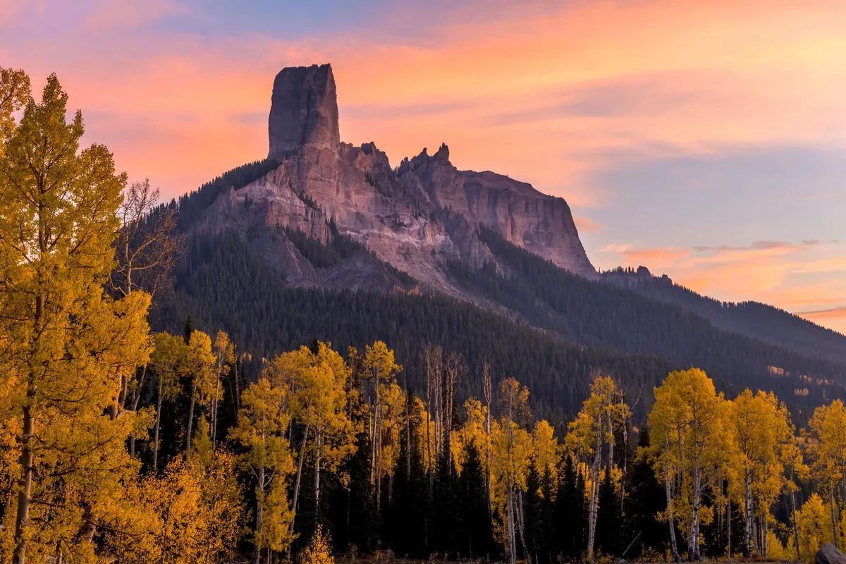 Mountain monolith above autumn aspens Rocky mountain monolith above golden aspens under a warm sunset sky